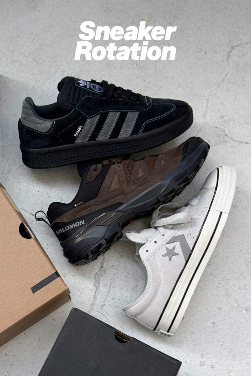 Tre paia di scarpe sportive disposte insieme: Adidas Samba in suede nero, Salomon marrone e Converse bianche con accenti grigi. Una scatola di cartone parzialmente visibile.