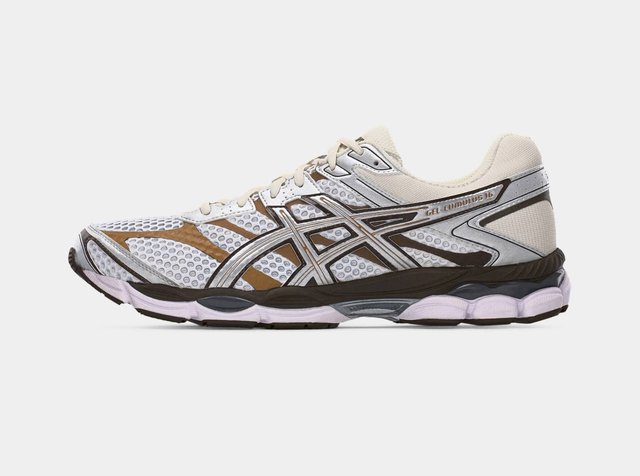 Zapatilla de correr ASICS Gel-Cumulus 16 en blanco y marrón con parte superior de malla, cierre de cordones y suela acolchada, mostrada de lado sobre un fondo blanco.