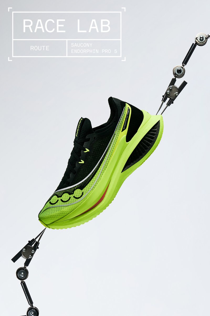 Chaussure de course Saucony Endorphin Pro 5 noire et vert fluo tenue par des bras mécaniques sur un fond uni avec le texte "Race Lab".
