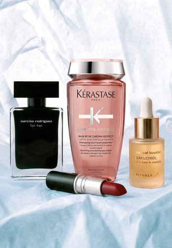 Perfum Black Narciso Rodriguez, różowy szampon Kérastase, żółta pipeta serum Bakuchiol oraz czerwona szminka MAC na jasnej tkaninie.