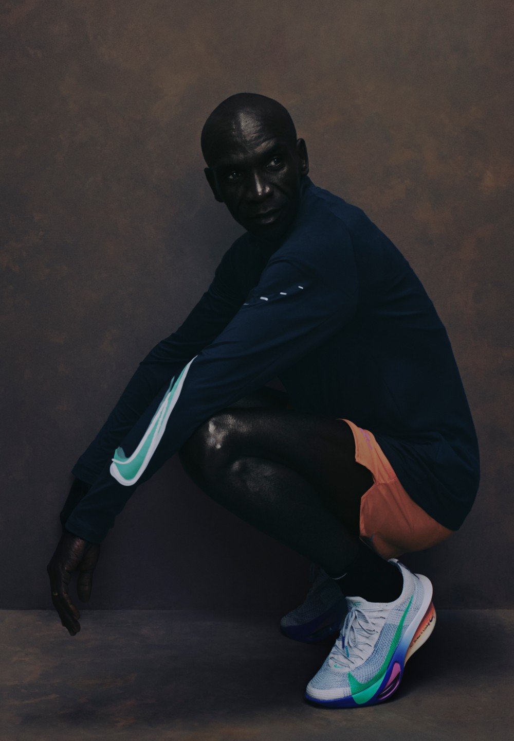 Sportliches Outfit mit einem marineblauen Langarmshirt mit grünen Akzenten, orangen Shorts und mehrfarbigen Sneakers mit einem strukturierten Mesh-Obermaterial.