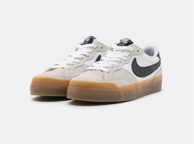 Lave sneakers har en kremfarget og hvit fargekombinasjon med svart Nike-logo, hvite snørebånd og en gjennomsiktig gummisåle.