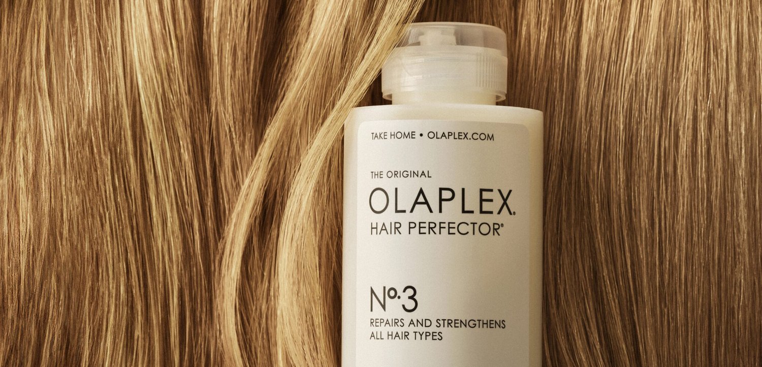 Bottiglia di Olaplex Hair Perfector n. 3 centrata su ciocche di capelli biondi lisci e lucenti sullo sfondo.