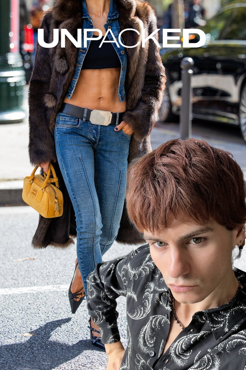 Een vrouw in een bruine bontjas en blauwe denim, met een gele handtas. Een jonge man in een zwart met patroon shirt staat op de voorgrond.
