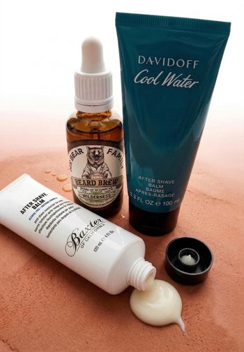 Drie verzorgingsproducten op een oppervlakte: BAXTER After Shave Balm tube met gemorste crème, MR BEAR Family Beard Brew flesje en DAVIDOFF Cool Water balm tube.