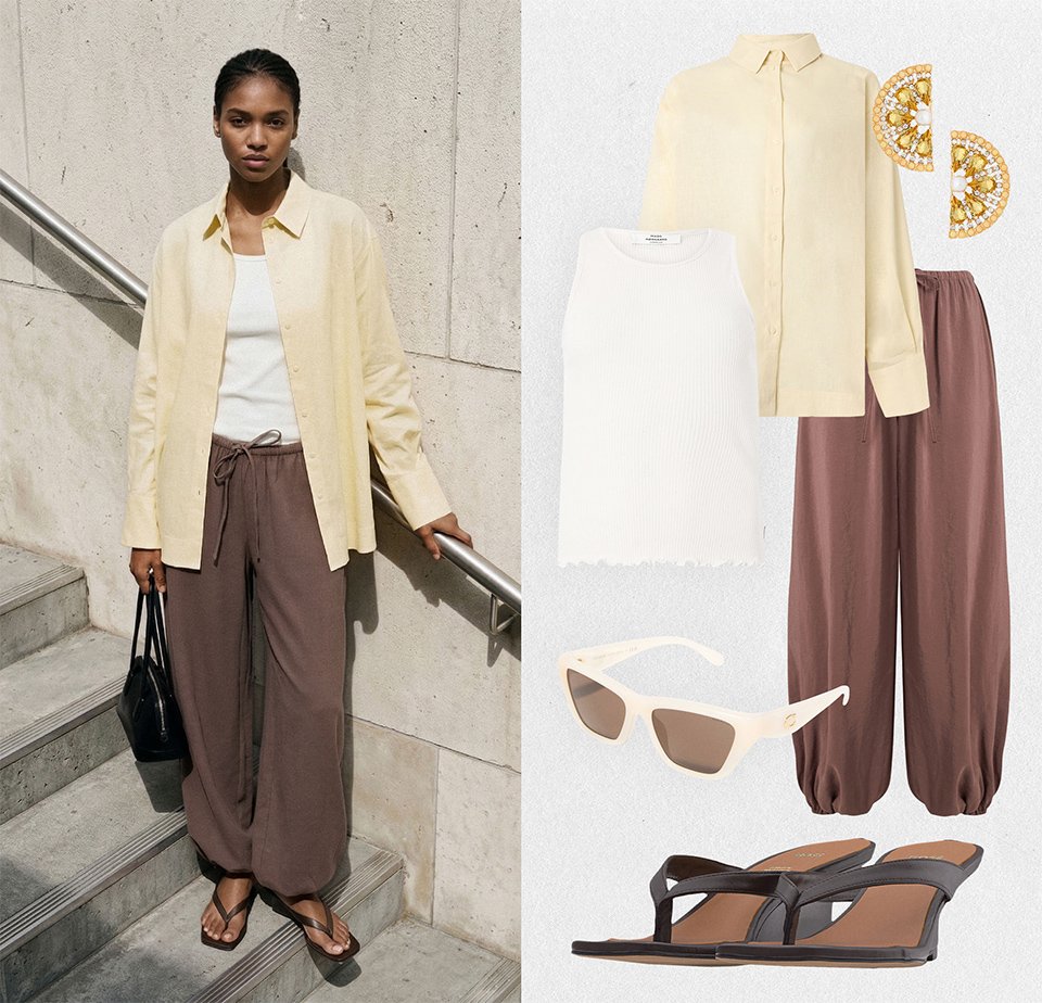 Γυναίκα που φοράει κρεμ πουκάμισο με κουμπιά, λευκό τοπ, φαρδιά καφέ παντελόνια, μαύρα σανδάλια, κρατά μαύρη τσάντα· στιλιζαρισμένη με γυαλιά ηλίου και χρυσά σκουλαρίκια.