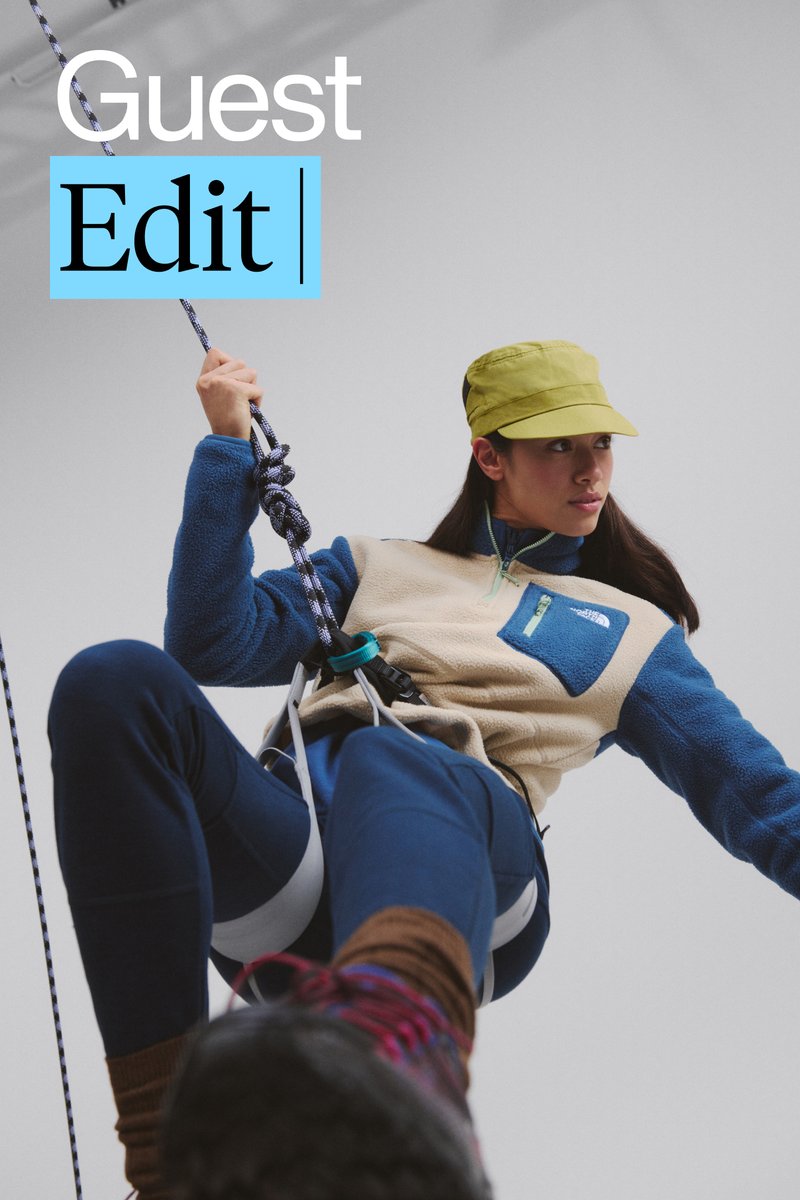Una persona con un forro polar azul y beige sube con un arnés, sosteniendo una cuerda. Lleva una gorra amarilla y se concentra en la ascensión.