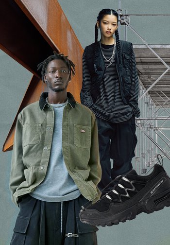 Zwei Models in gedämpften Streetwear-Tönen stehen in der Nähe von rostigem Stahl und Gerüst, während im Vordergrund ein schwarzer Salomon Sneaker zu sehen ist.