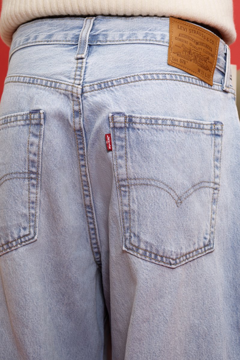Lichtblauwe Levi's jeans vanuit de achterkant met leren merkpatch bij de taille en een rode stoffen label aan de rechter achterzak.
