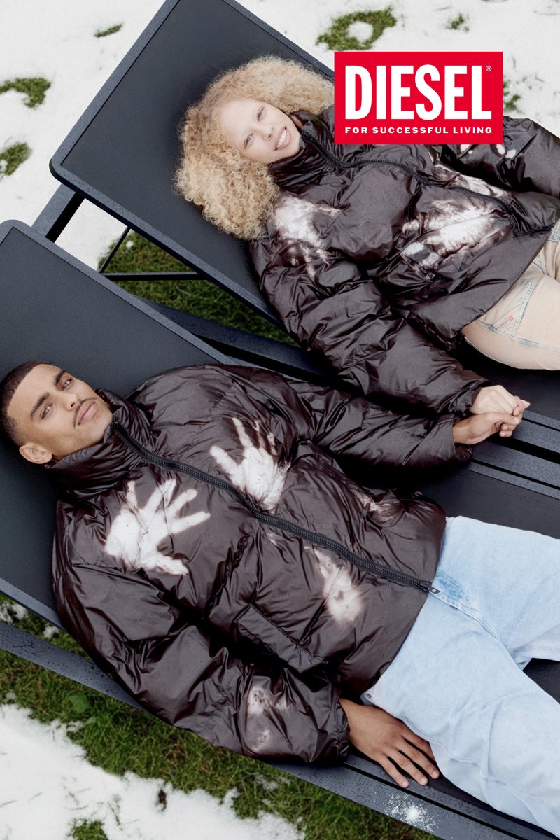 Bruine donsjassen met handafdrukontwerpen, gedragen door twee personen die op ligstoelen liggen. Ze zijn buiten, met gras en sneeuw zichtbaar.