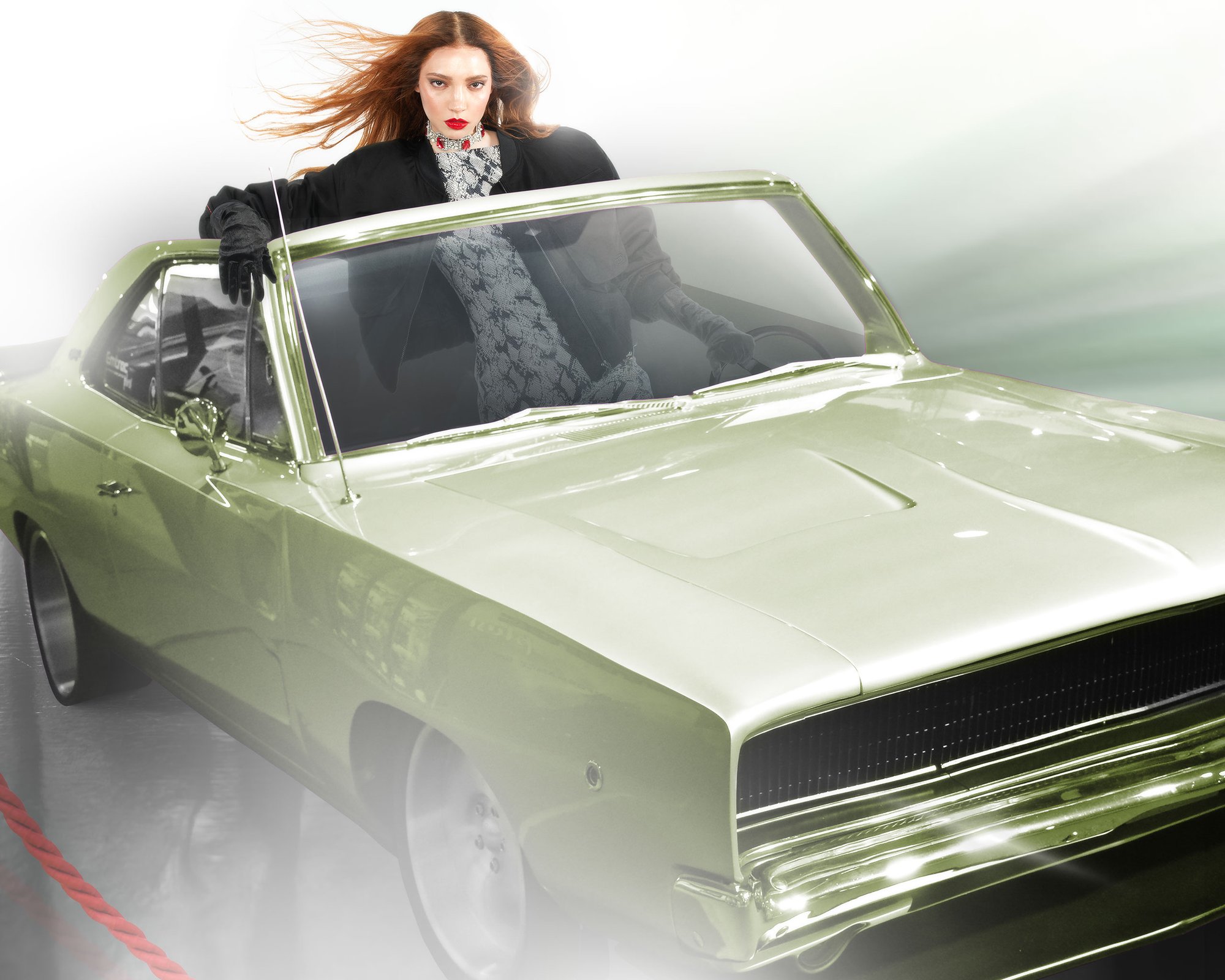 A woman with long hair leans against a vintage green car, wearing stylish gloves and a patterned outfit, exuding confidence and attitude.