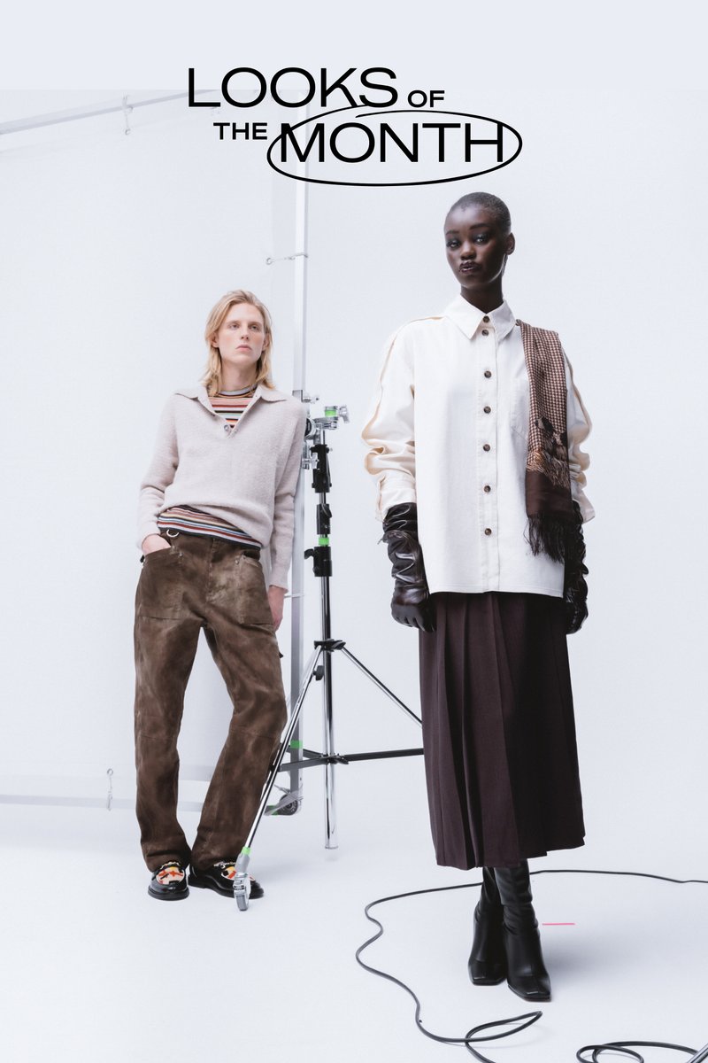 Due modelle posano in outfit alla moda: una in un maglione a righe e pantaloni marroni, l'altra in una camicia bianca e guanti neri.
