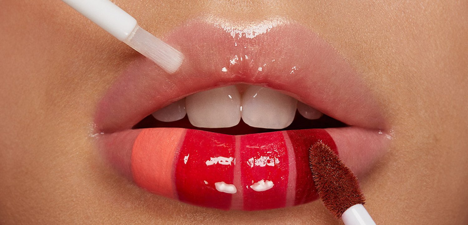 Plano cerrado de labios con tres tonos de brillo labial aplicados con dos aplicadores diferentes.