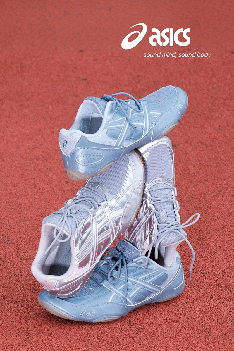 Pair of silver and light blue Asics running shoes stacked on red textured surface with Asics logo and slogan above.