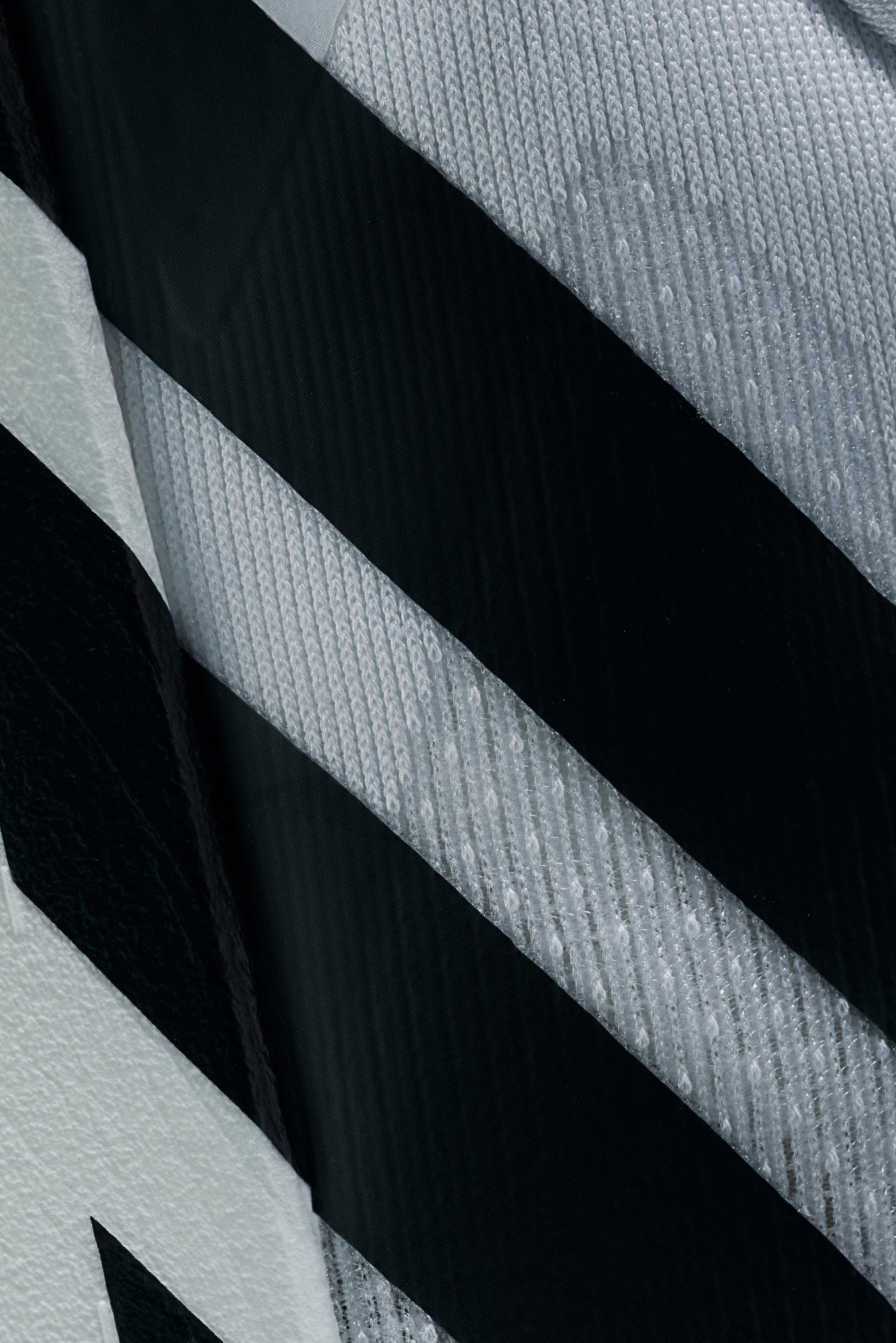 Primer plano de un material texturizado con rayas diagonales en blanco y negro, que resalta los detalles de la tela y los patrones variados.