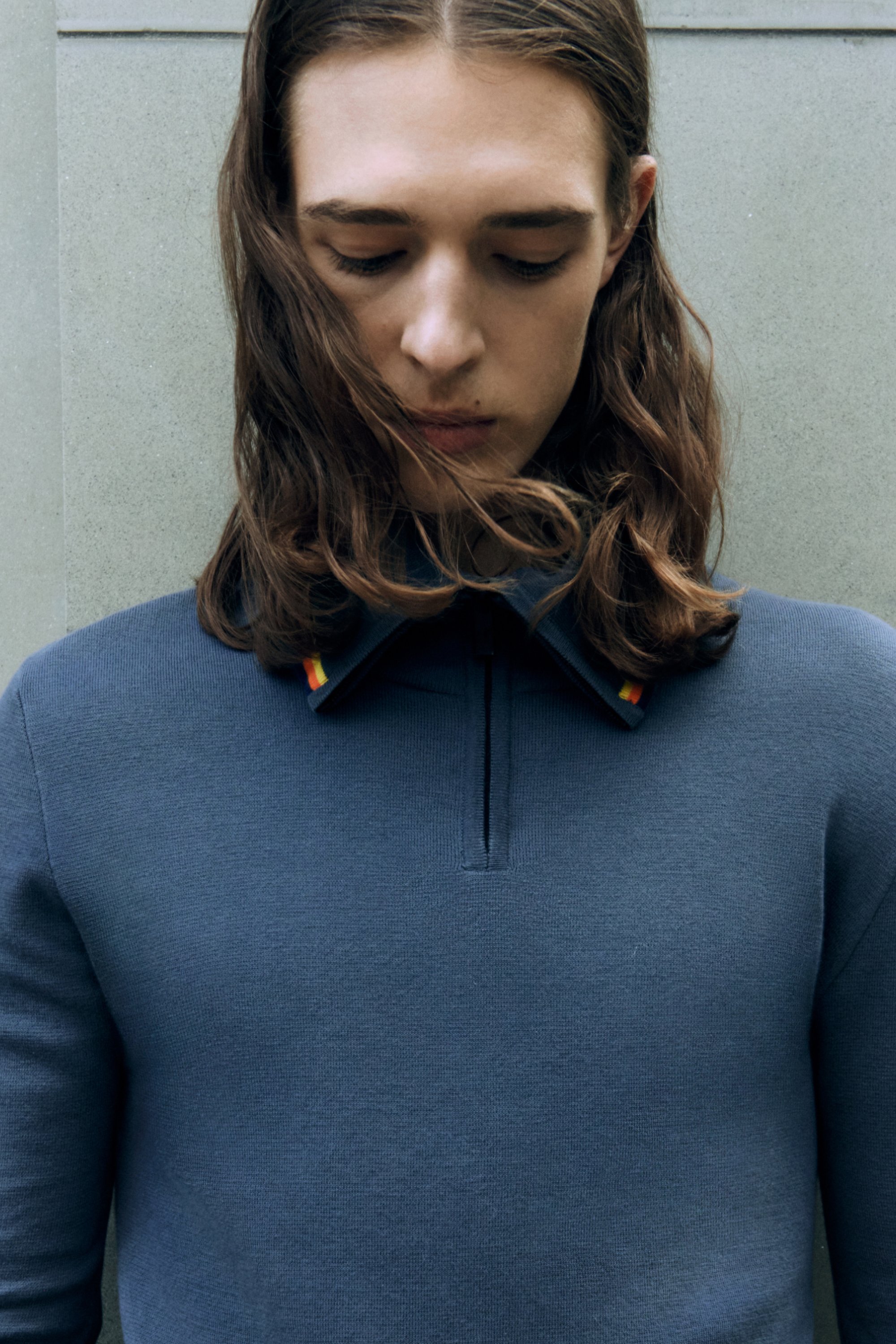 Dunkelblaues langärmliges Hemd mit Viertel-Reißverschluss und Kragen, der am Kragenrand mit bunten Streifen verziert ist; gestrickte Textur.