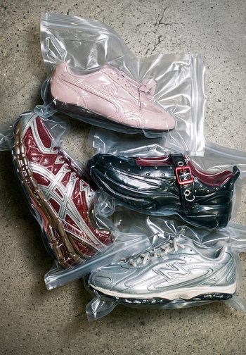 Four different sneakers in transparent vacuum-sealed plastic bags on a cracked concrete surface.