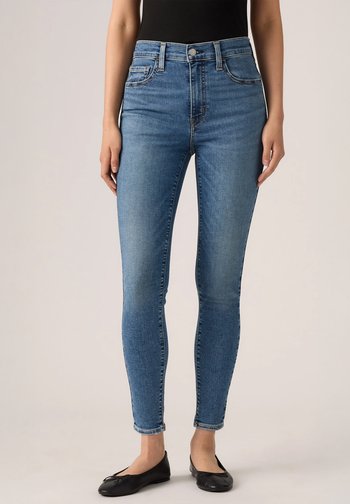 Tynne blå jeans med høy midje, laget av denim, med frontknapping, beltesløyfer og klassisk femlommers design.