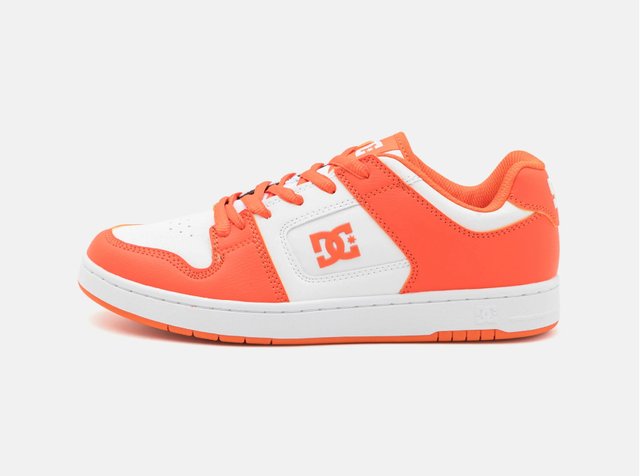 White and orange sneaker with a DC logo, featuring a textured upper, round toe, and laces, set against a plain background.