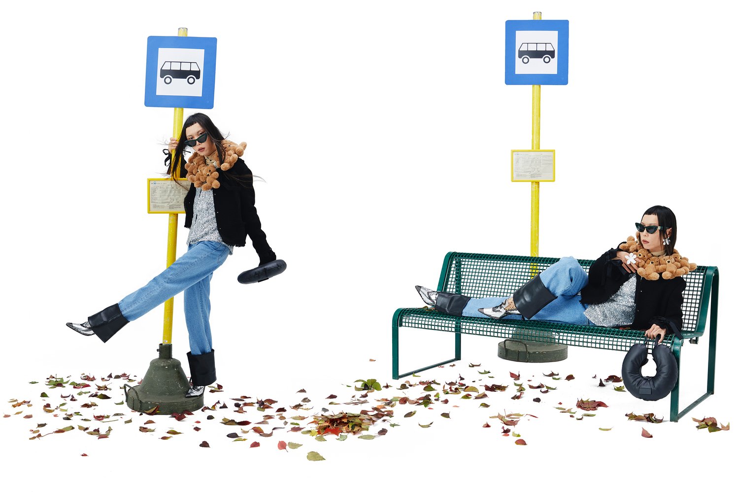 A woman with sunglasses leans against a bus stop, playfully balancing a teddy bear and a rubber tire, surrounded by colorful autumn leaves.