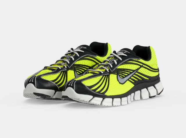 Paire de chaussures de running Nike jaune néon et noire avec semelles blanches et logos Swoosh gris sur fond blanc.
