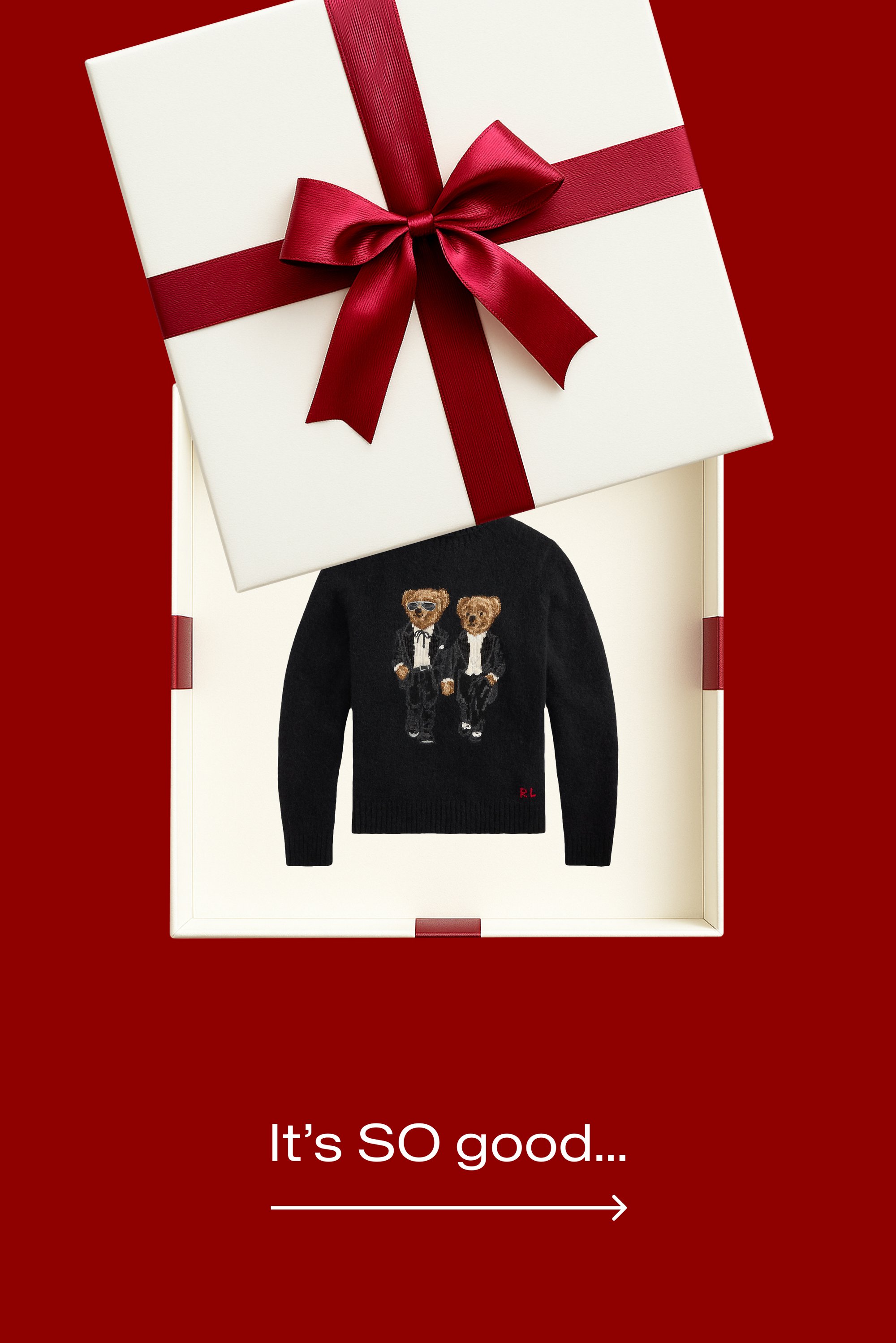 Scatola regalo bianca con nastro rosso parzialmente aperta che mostra un maglione nero con due orsetti in smoking all'interno su sfondo rosso. Testo: "È COSÌ buono..."