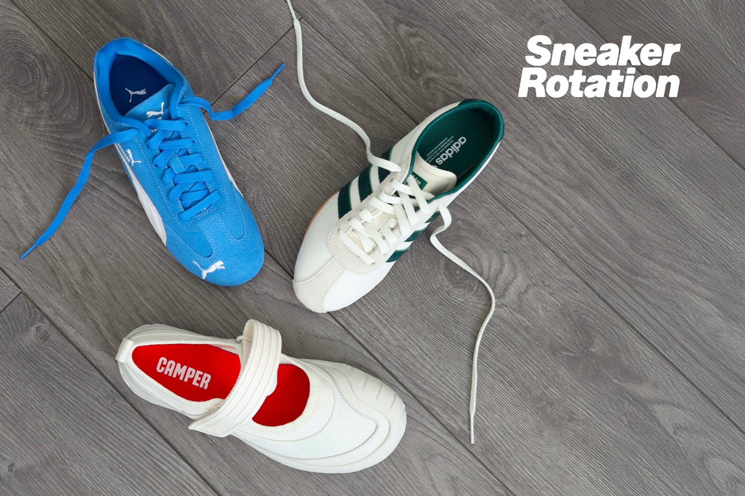 Tres estilos de zapatillas: unas Puma azules con cordones, unas Adidas blancas con rayas verdes, y unas Camper blancas sin cordones, exhibidas sobre un suelo de madera.