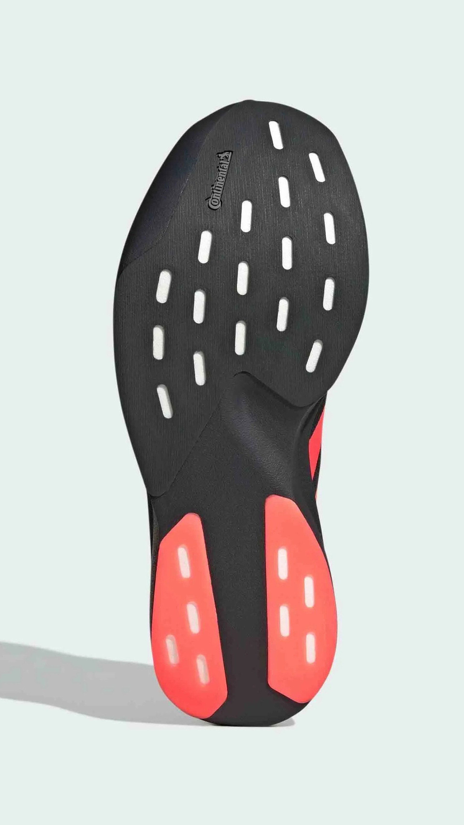 Suela de zapato negra con acentos rojos y patrones de tracción en blanco. Presenta el logo "Continental" cerca del área del dedo del pie.