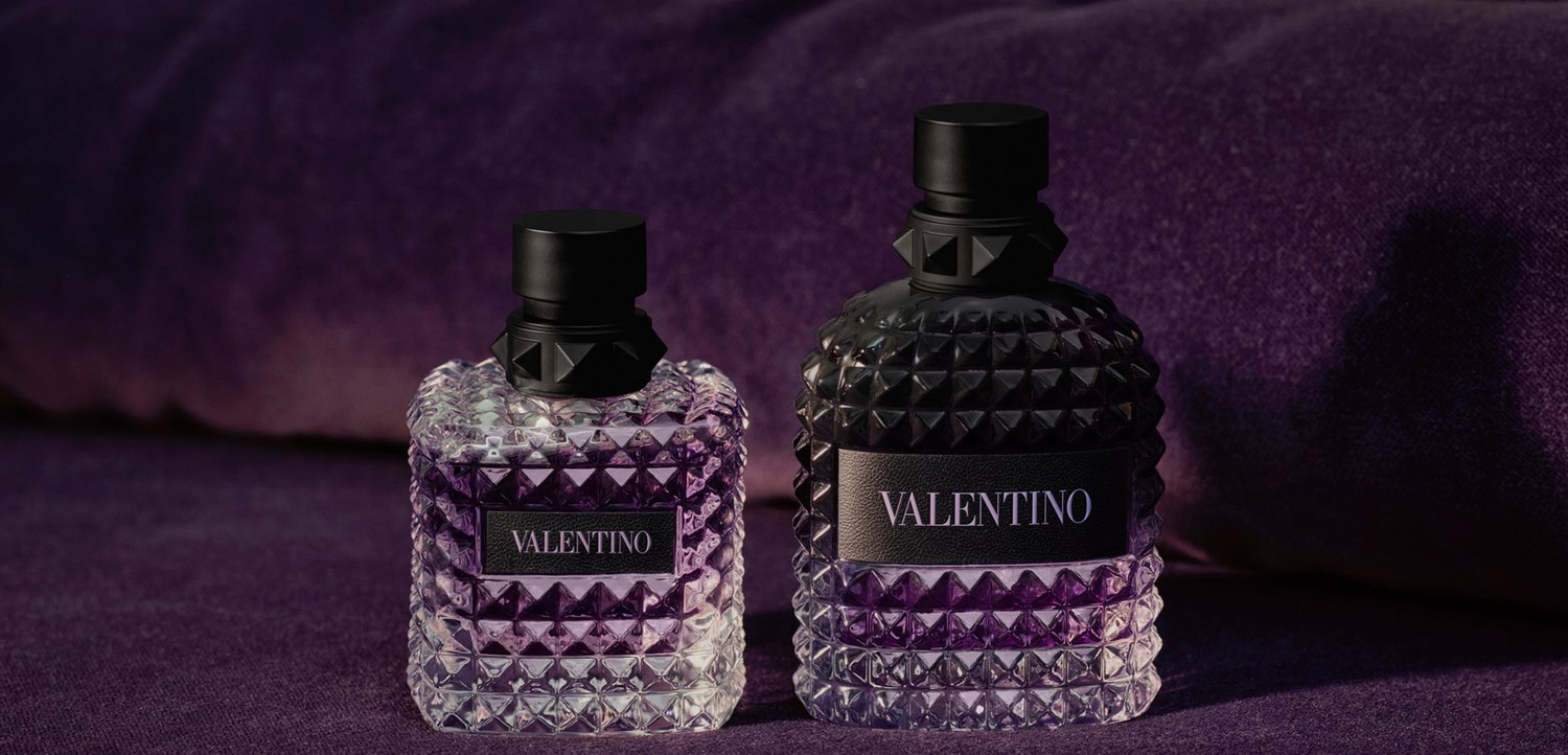 Twee Valentino-parfumflesjes met gestructureerd glas en zwarte doppen staan op een paarse stoff achtergrond.