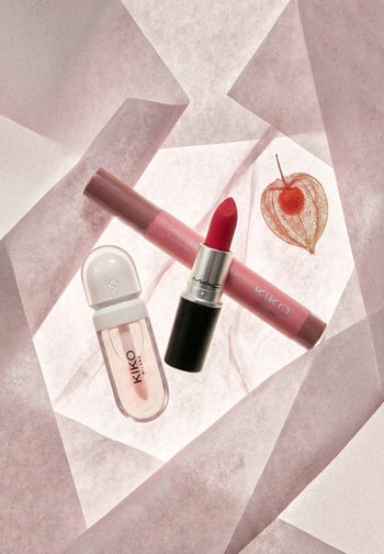 Czerwona szminka MAC, różowy marker do ust KIKO oraz przezroczysty błyszczyk KIKO ułożone na różowej przezroczystej tkaninie z delikatną pomarańczową miechunką.