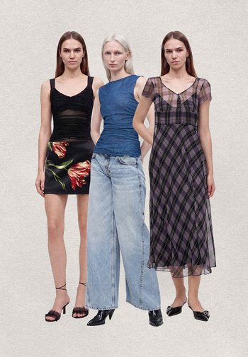 Trois femmes debout côte à côte portant une jupe noire fleurie, un top bleu sans manches avec un jean large, et une robe midi à carreaux violette.
