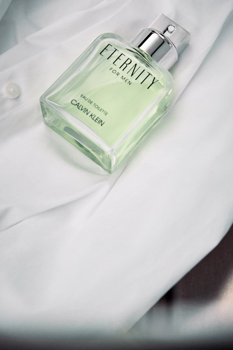 Calvin Klein Eternity for Men Eau de Toilette perfume bottle with pale green liquid on white fabric.