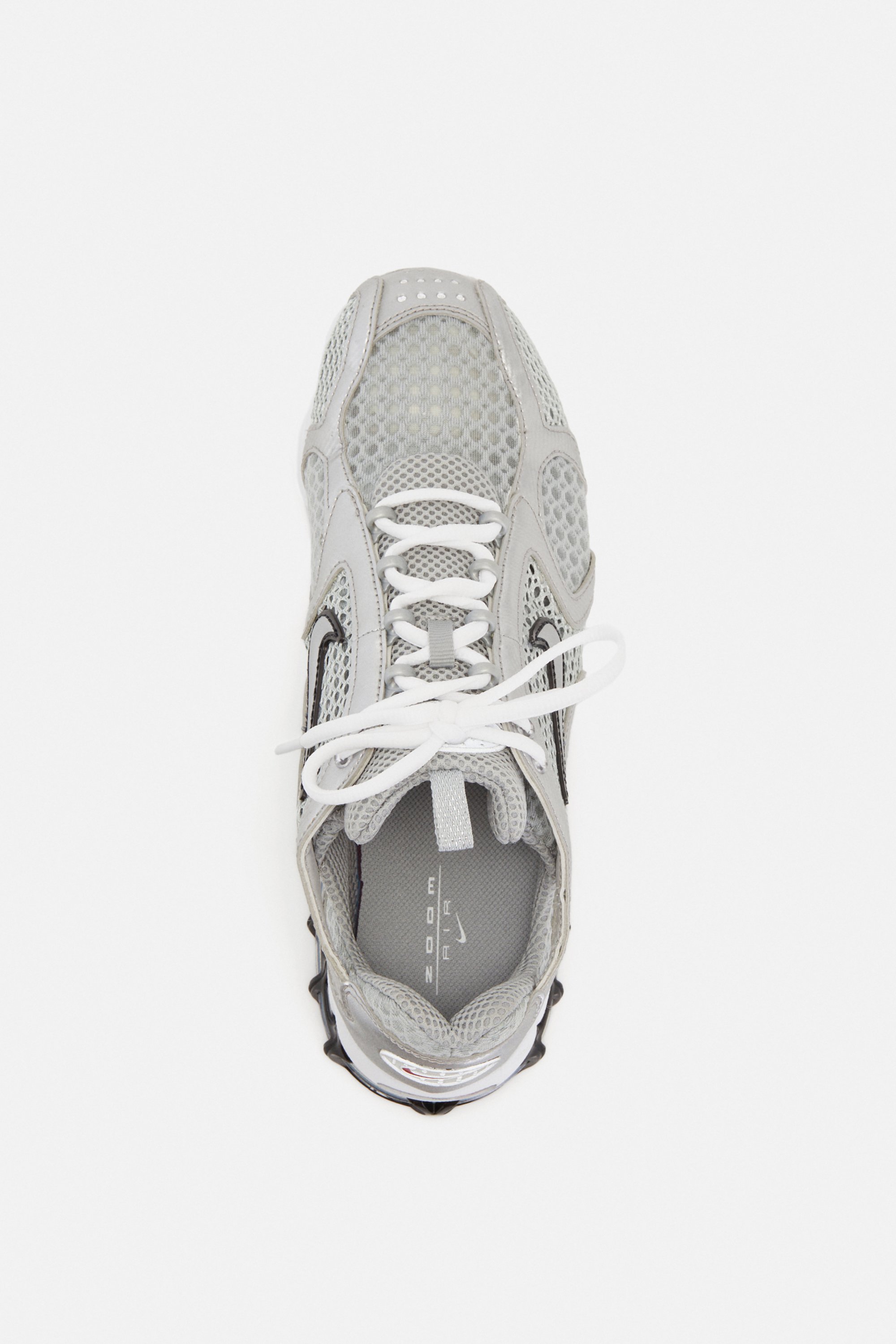 Grijze sportief schoen met gaasdetails en witte veters, bekeken vanuit boven tegen een witte achtergrond, die het ontwerp en de structuur toont.