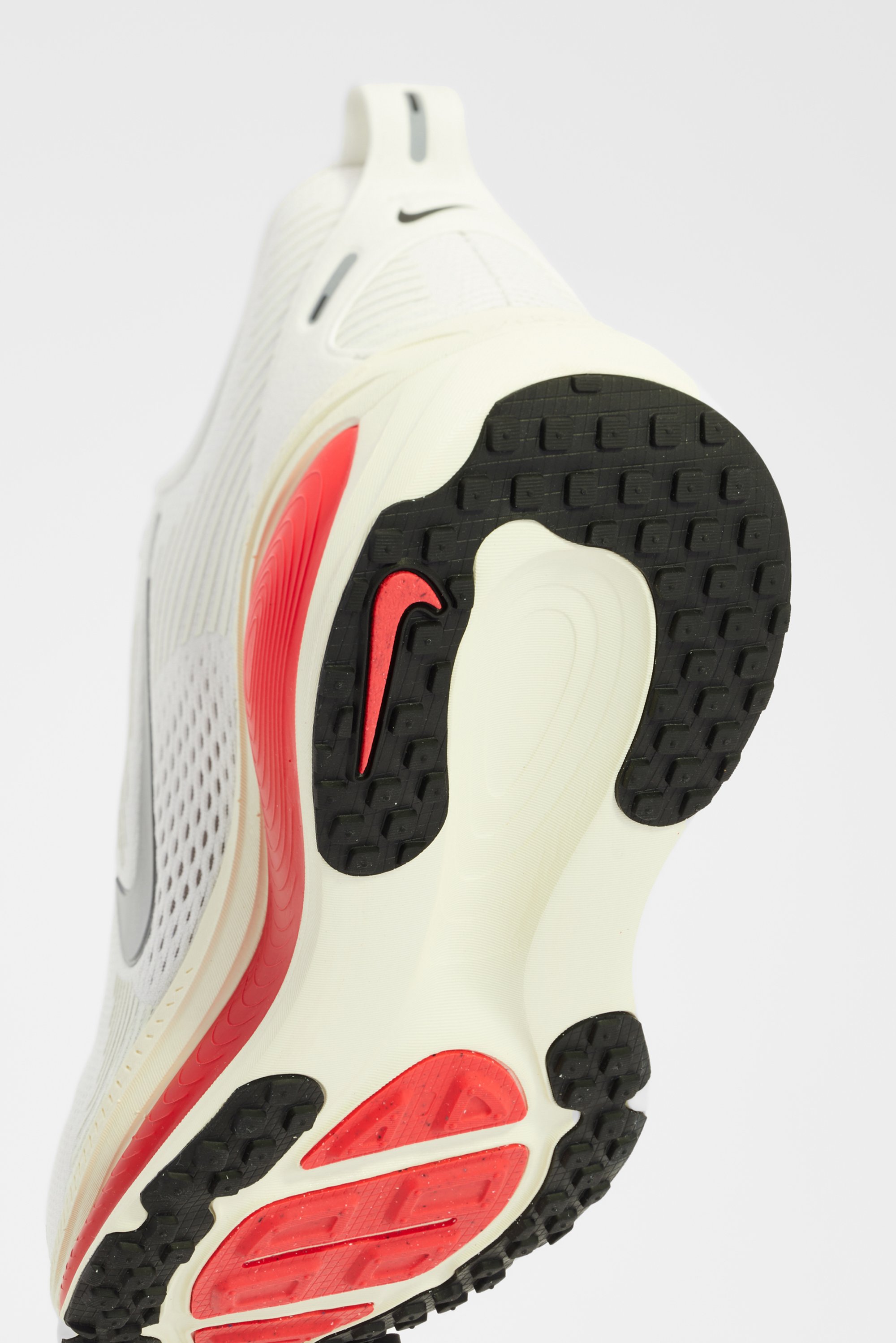 Suela de una zapatilla Nike blanca, con acentos en negro y rojo, y una superficie texturizada para mejorar el agarre y el soporte.