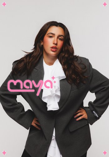 Blazer gris surdimensionné avec des épaules structurées, portant une blouse blanche à volants en dessous et des ongles noirs avec des accents floraux. Logo en rose.