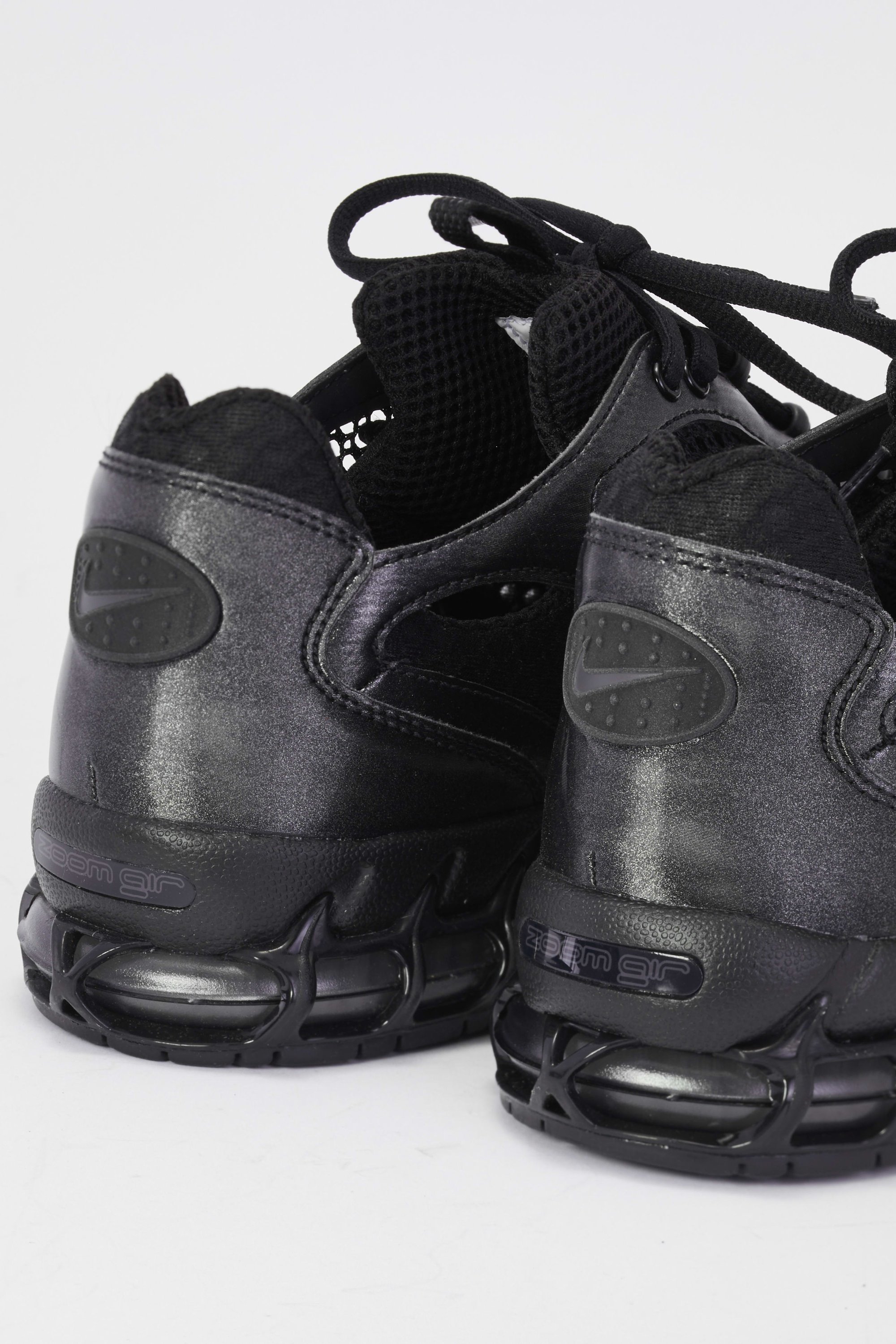 Zwarte sportieve schoenen hebben een slank ontwerp met een textuurafwerking en comfortabel gekussen zolen, wat een moderne, sportieve stijl tentoonstelt.