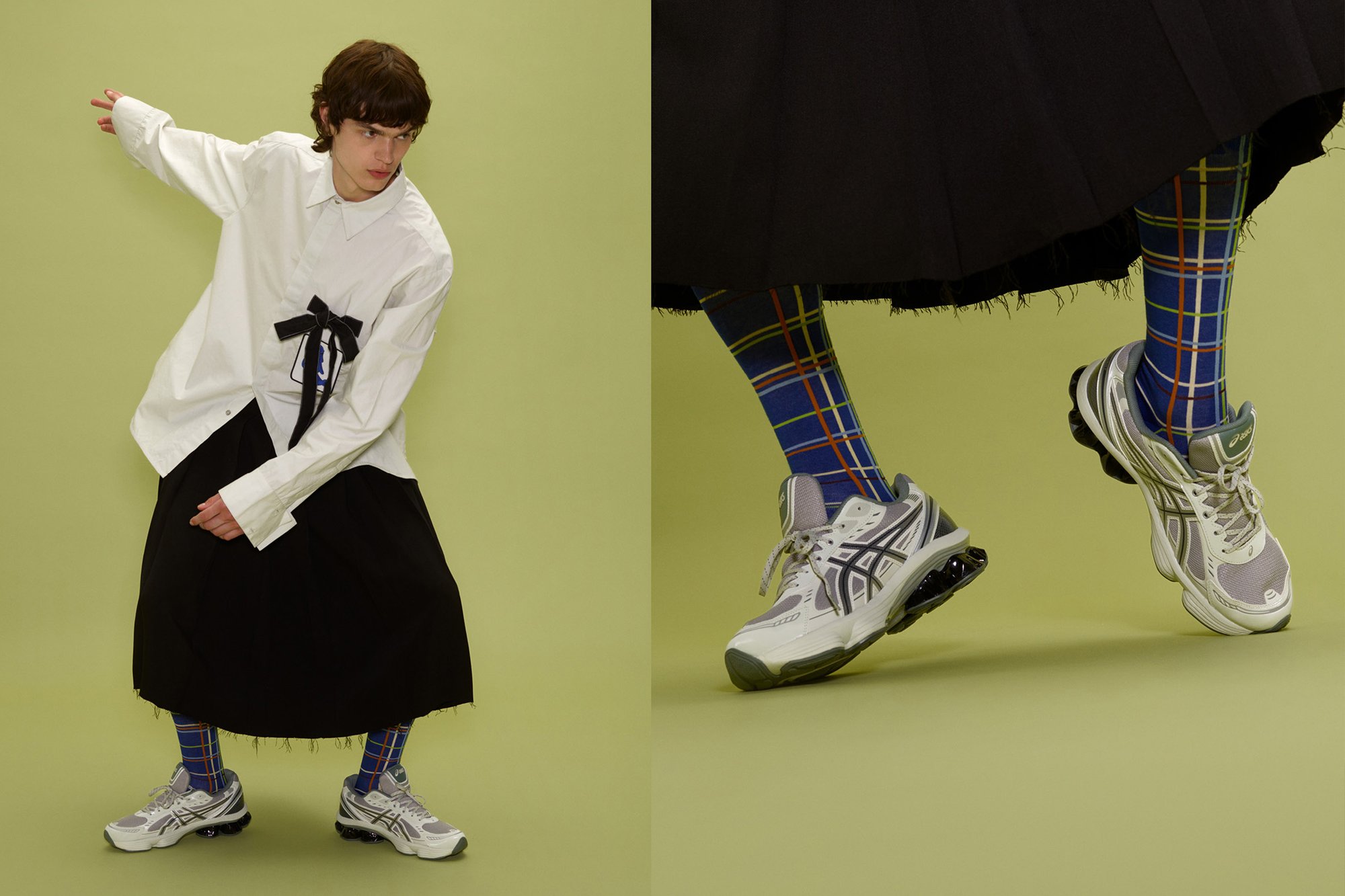 Camisa blanca de manga larga con detalle de lazo negro, falda negra con pliegues, leggings de cuadros azules y grises, y zapatillas deportivas grises con acentos negros.