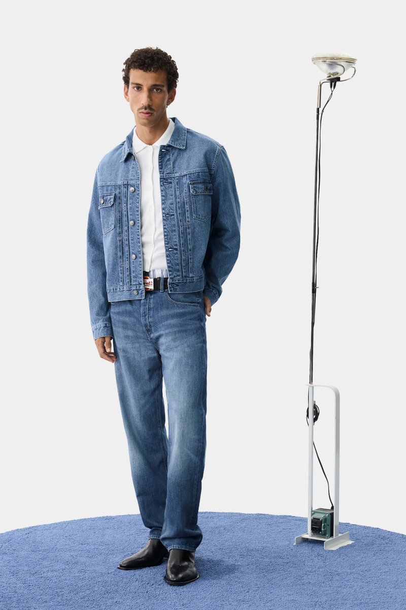 Leren spijkerjas en bijpassende spijkerbroek in lichtblauw, gecombineerd met een wit shirt en zwarte schoenen. Eenvoudig ontwerp met klassieke details.