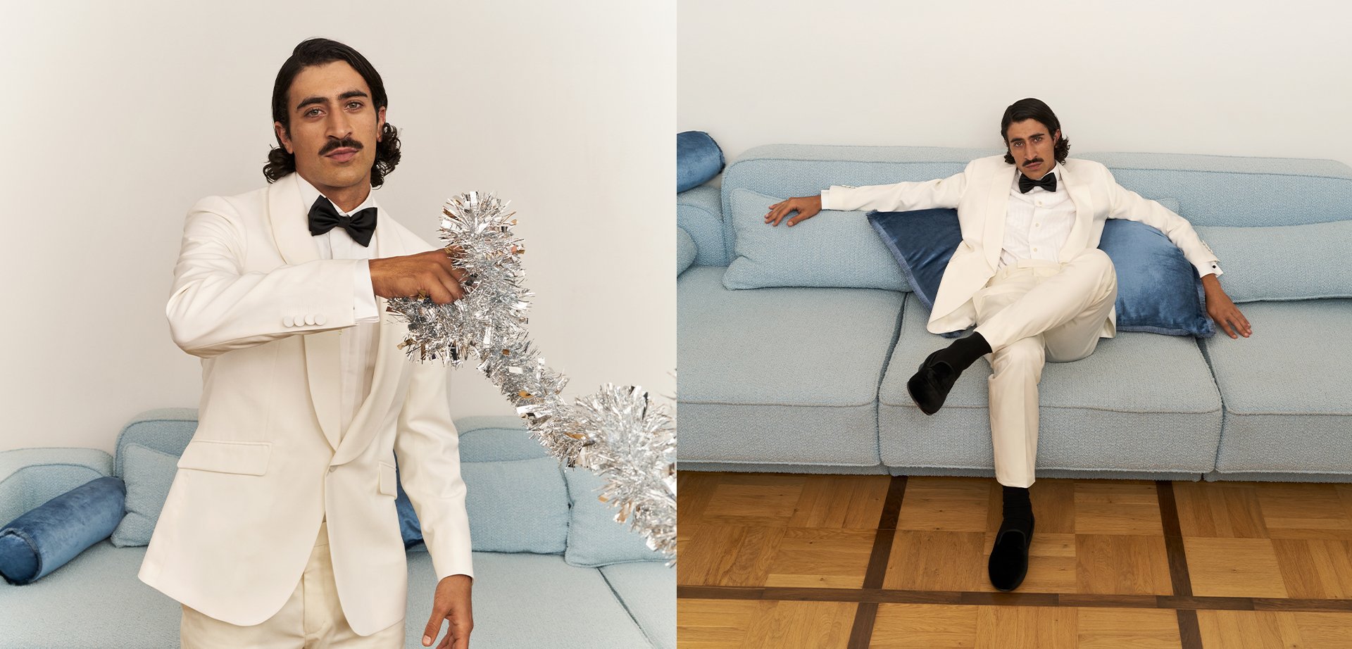 White tuxedo with black bow tie; holding silver tinsel. Light blue sofa, striped cushions, wooden floor with a grid pattern.