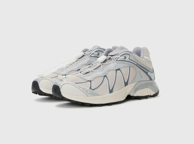 Ελαφριά παπούτσια τρεξίματος σε γκρι και άσπρο. Διαθέτουν επάνω μέρος από δίχτυ, λαστιχένια σόλα και ελαστικά κορδόνια. Στρογγυλερή μύτη και υφή με μοτίβα.