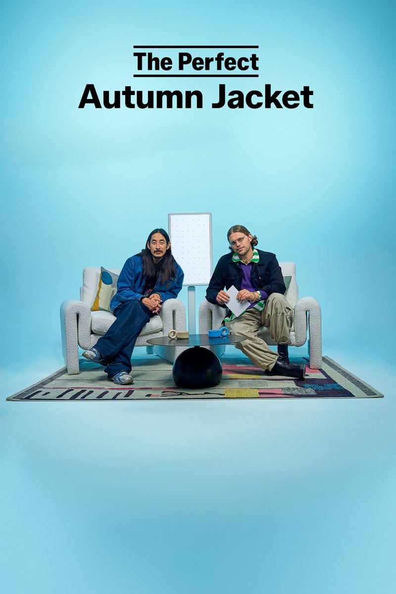 Twee personen zitten op moderne stoelen in een helderblauwe omgeving, terwijl ze een ontwerpconcept bespreken met een minimalistische tafel en een kleurrijk tapijt in de buurt.