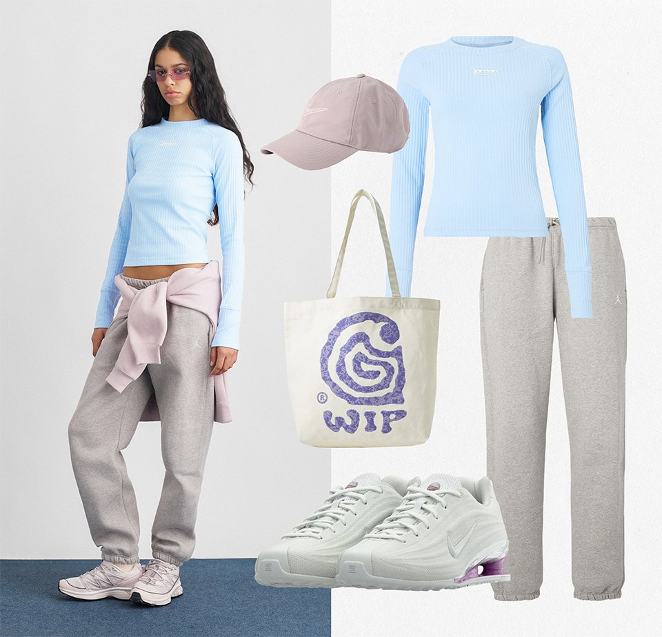 Frau trägt ein hellblaues Langarmshirt, graue Jogginghosen, pinke Turnschuhe und lila getönte Brille, mit einem passenden pinken Sweatshirt um die Taille gebunden.