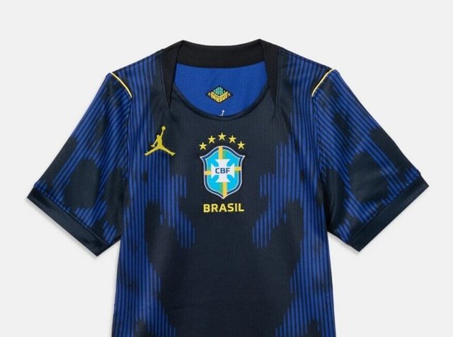 Kék-fekete brazil focimez sárga díszítéssel, CBF címerrel, Jordan logóval és négy csillaggal a címer felett, egyszínű háttéren.
