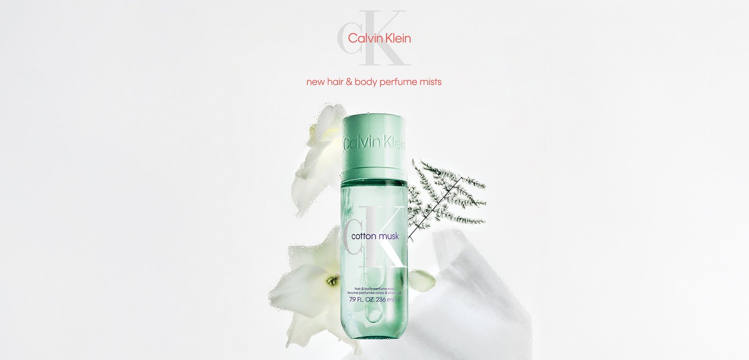 Flesje haar- en lichaamsparfum mist Calvin Klein Cotton Musk, omgeven door witte bloemen en groene varen op een witte achtergrond.