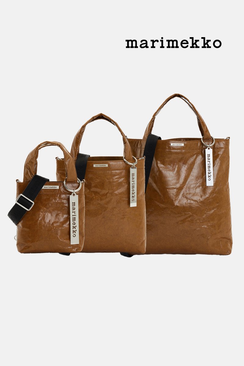 Three brown Marimekko tote bags of varying sizes are displayed, featuring sturdy handles and a stylish design with brand tags attached.