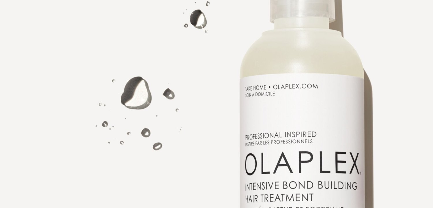 Botella de Olaplex Intensive Bond Building Hair Treatment con gotas de agua sobre un fondo blanco.