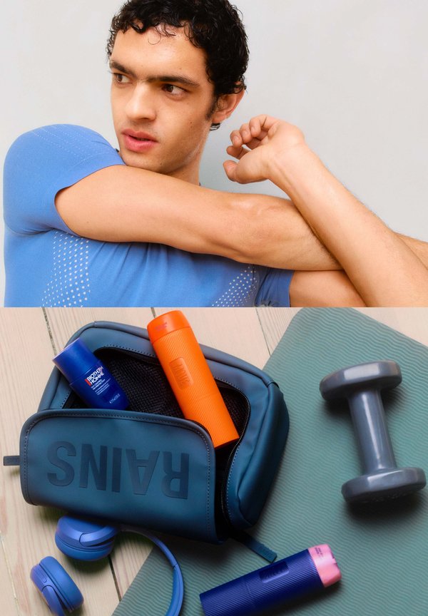 Sporttas in donkerblauw met de tekst "RAINS", gevuld met oranje en blauwe containers, gecombineerd met een grijze dumbbell en blauwe koptelefoon op een gestructureerde mat.