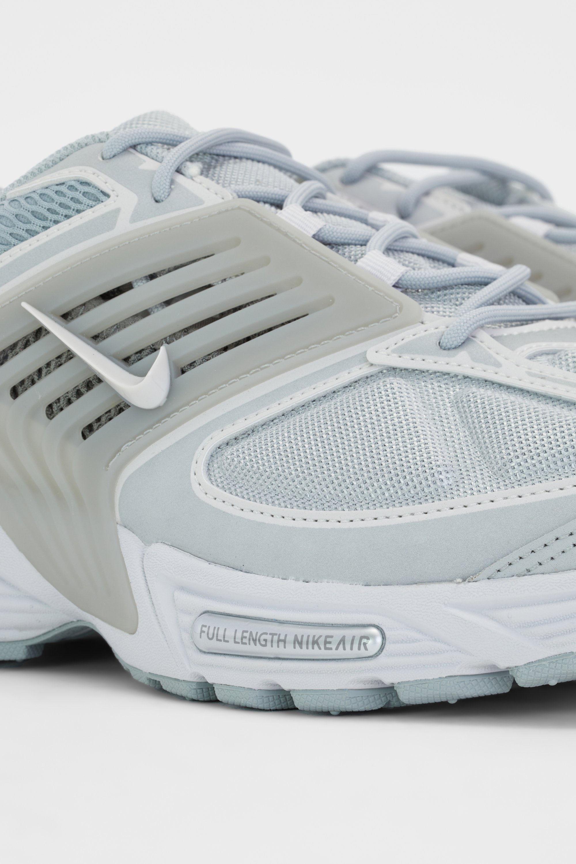 Lichtgrijze Nike atletiekschoenen zijn gemaakt van gaas- en suède materialen, met een opvallende gevoerde zool waarop het label "FULL LENGTH NIKEAIR" staat.