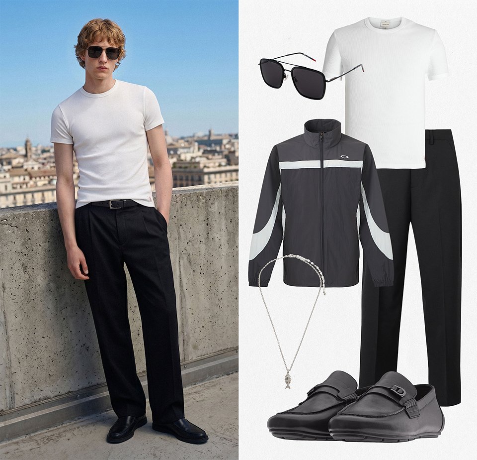 Jeune homme portant un t-shirt blanc, un pantalon noir, des chaussures noires et des lunettes de soleil, debout devant un mur en béton avec un paysage urbain.