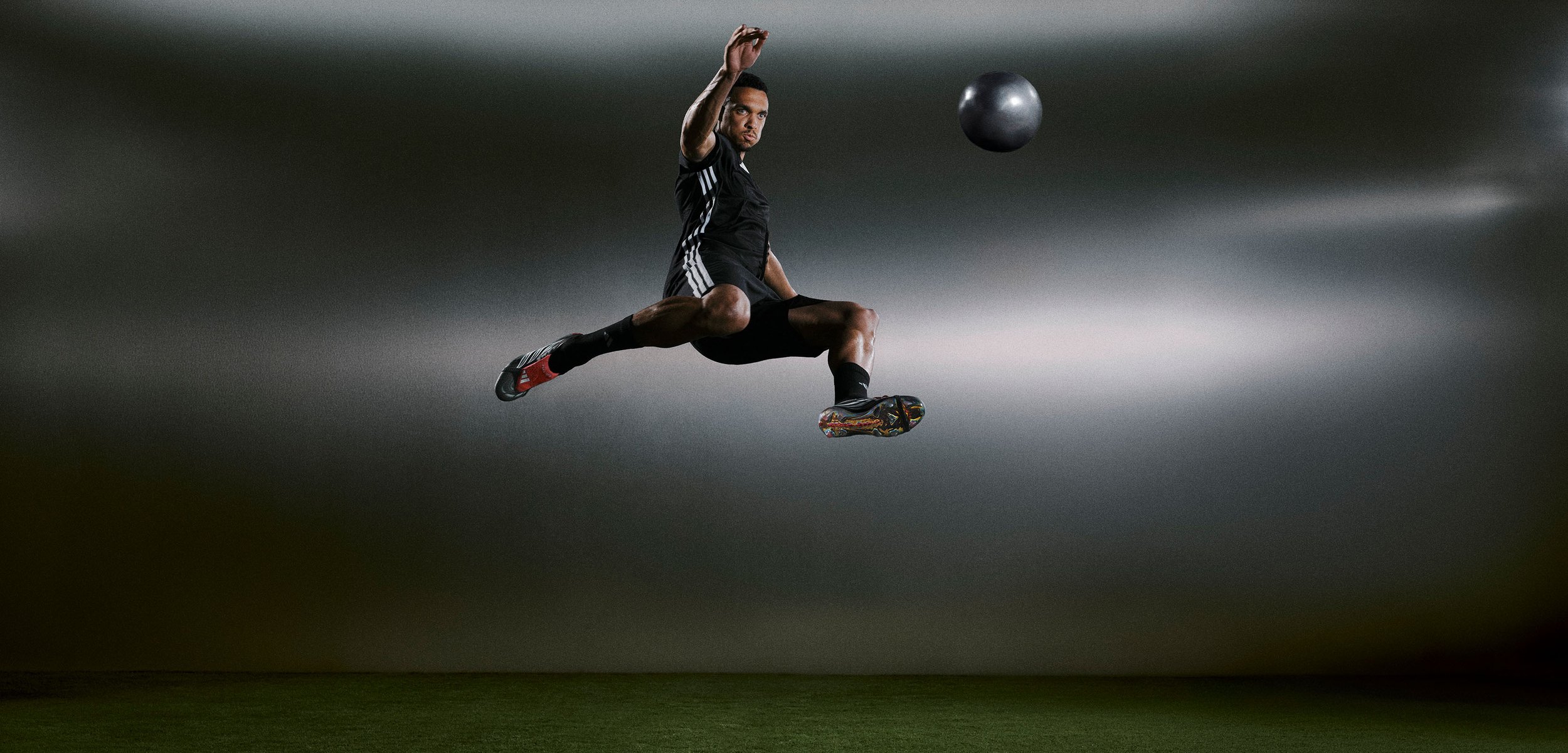 Egy sportoló fekete sportöltözetben levegőben ugrik, színes stoplikat mutatva. Egy nehéz labda lebeg az előtérben, gradiens háttér előtt.